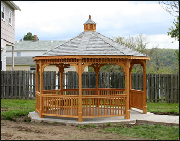 14 Treated Pine Octagon Gazebo shown with No Deck, 2 x 2 Square Railings, 2 Coats Cedar Tone Stain/Sealer, Old English Pewter Asphalt Shingles and 5 Bench Sections