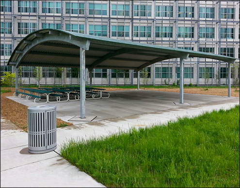 40 x 50 All Steel Curved Roof pavilion shown with prime painted tube steel frame, 24 gauge exposed fastener metal roof and 6 polypropylene Picnic tables. 